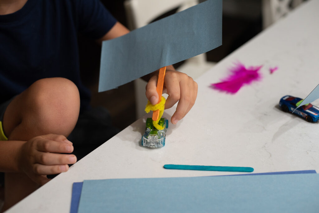 kid holding a wind powered car made from craft supplies